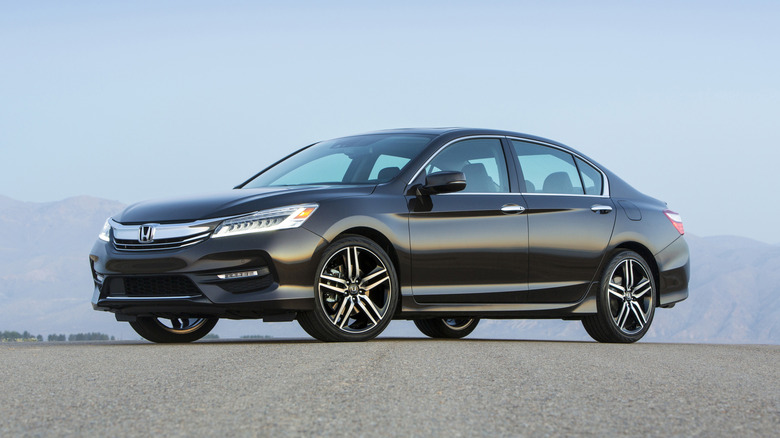 A black 2017 Honda Accord Sedan Touring seen in left front three-quarter view parked in front of distant hazy hills