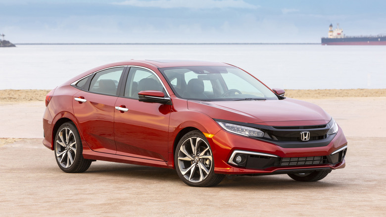 A red 2021 Honda Civic Sedan Touring model seen in right front three-quarter view parked on a beach