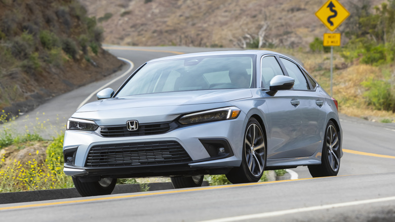 A gray 2024 Honda Civic Sedan seen from left front three-quarter view driving on a twisty road
