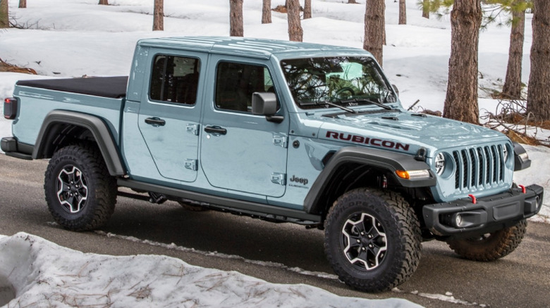 A pale green Jeep Gladiator Rubicon among trees in a snowy forest