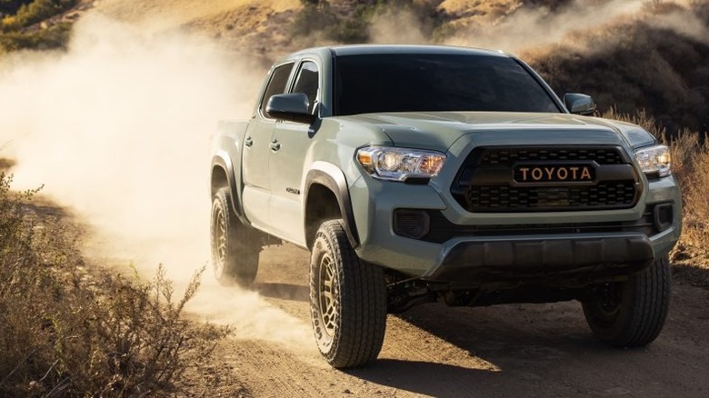 A 2022 Toyota Tacoma off-roading with a cloud of dust behind it