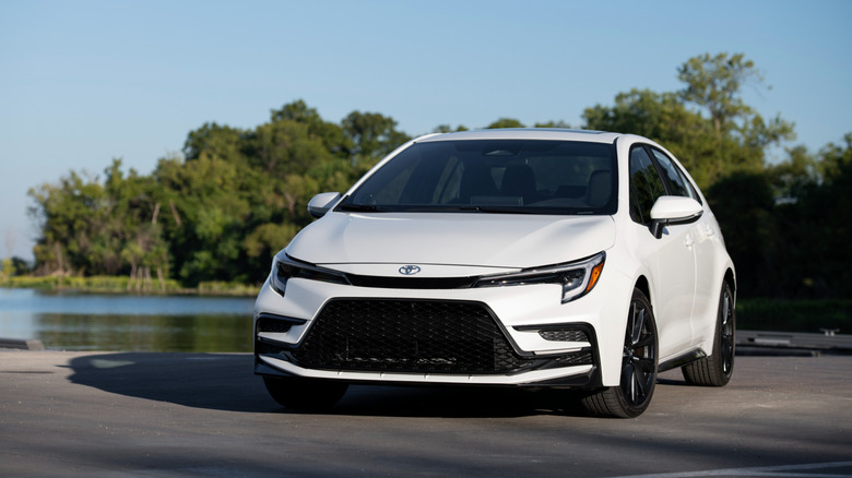 White 2026 Toyota Corolla sedan left front quarter view with lake and trees in background
