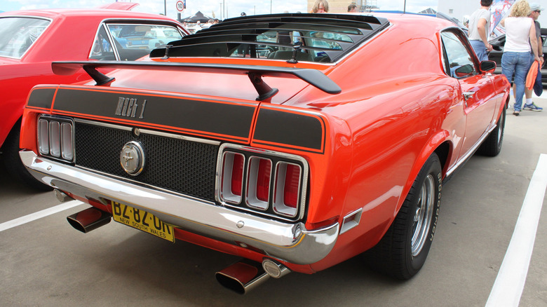 A Ford Mustang Mach 1 sits parked with black rear window louvers visible.