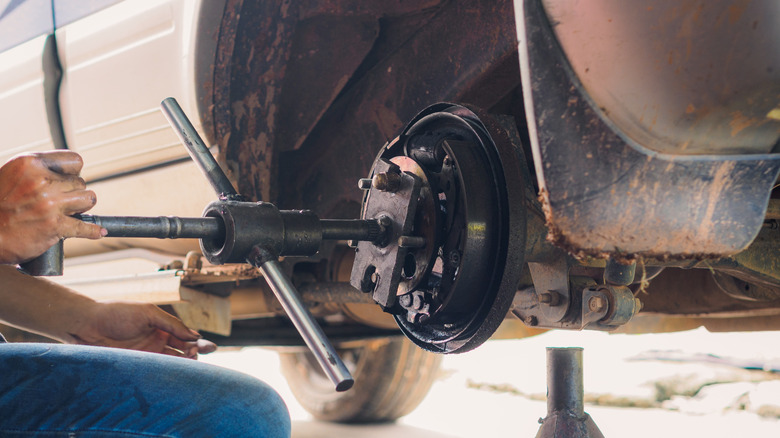 Close up image of a mechanic using a hub puller to remove an axle.