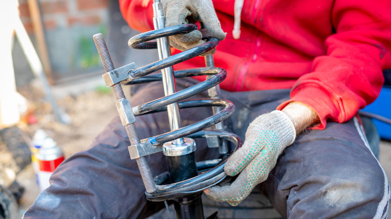 Mechanic uses a spring compressor to safely handle coil springs.