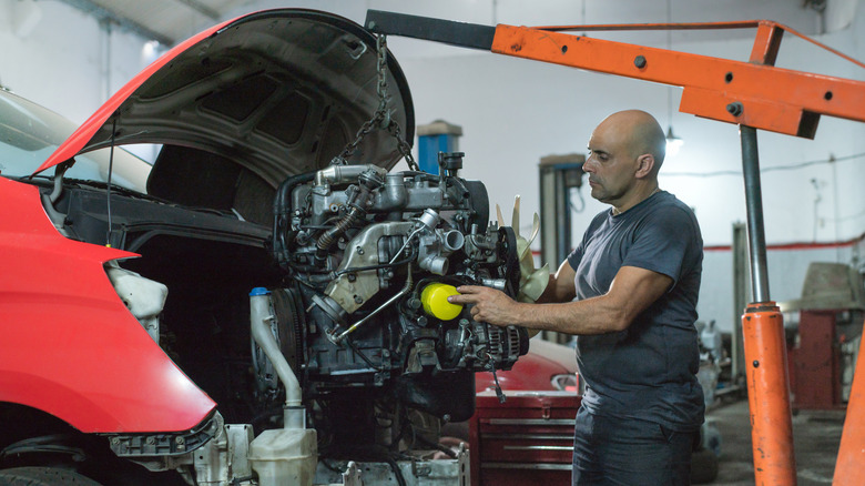A mechanic uses an engine hoist to install an engine.