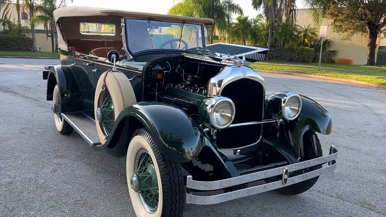 A dark green 1926 Chrysler Imperial Touring convertible sedan with its gullwing hood opened.