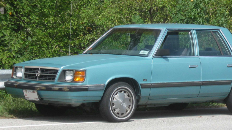 A blue Dodge Aries parked on the side of road