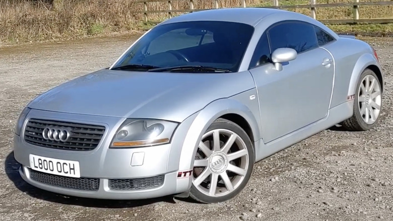 A silver Audi TT 225 Quattro sits parked in a rocky lot.
