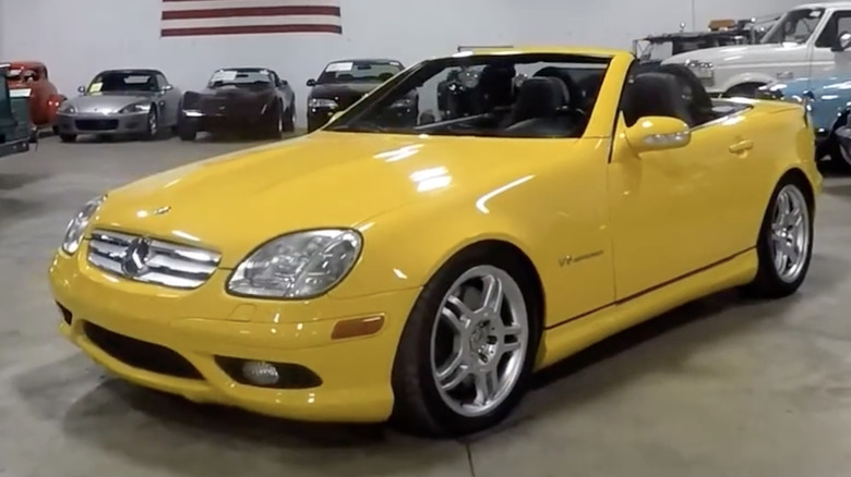 A yellow Mercedes-Benz SLK32 AMG sits in a garage.
