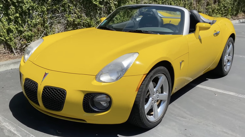 A yellow Pontiac Solstice GXP sits parked.