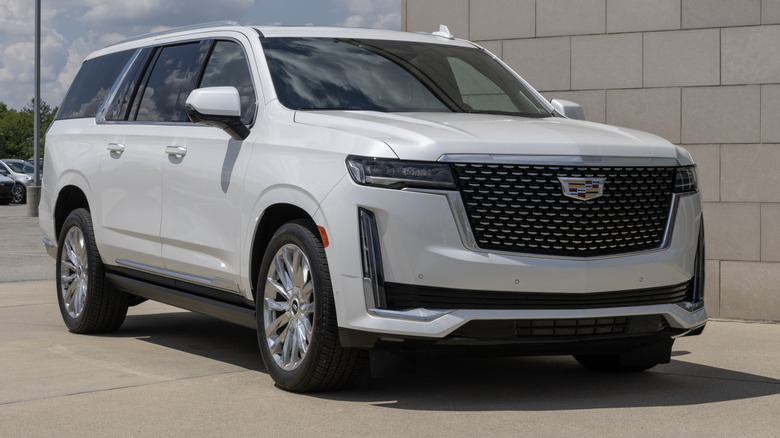 A white Cadillac Escalade ESV parked near a building.