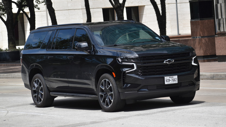 A black 2024 Chevrolet Suburban sits on the street.