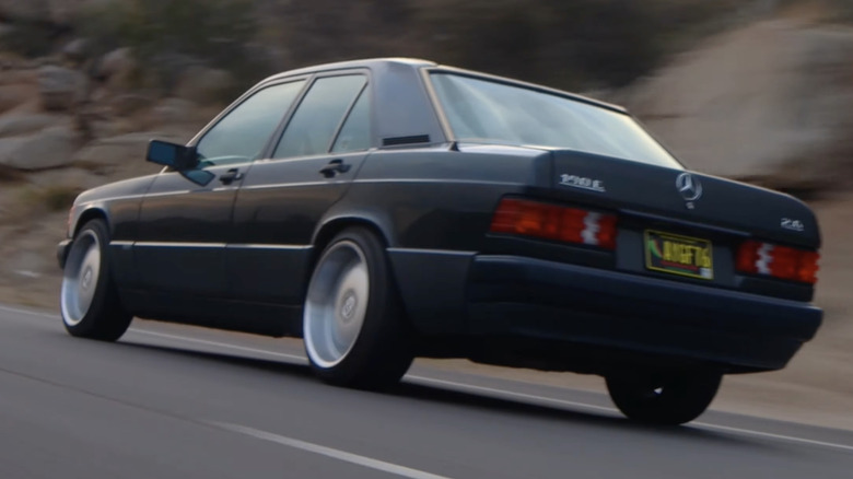 A Mercedes-Benz 190E drives on a mountain road.