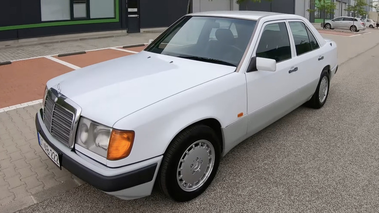 A Mercedes-Benz W124 sits parked on a street.