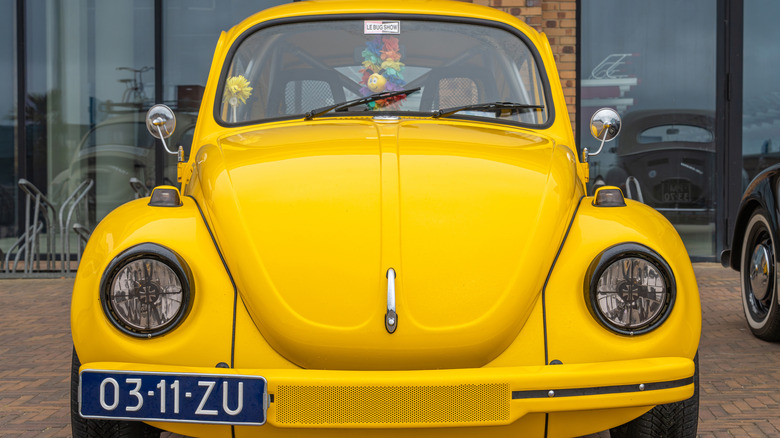 A yellow VW Beetle is seen from the front.