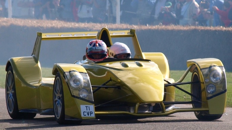 A yellow Caparo T1 open-cockpit hypercar driving past spectators at the 2008 Goodwood Festival of Speed