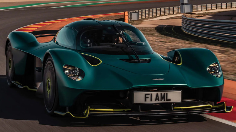 An Aston Martin Valkyrie in British Racing Green with lime accents cornering hard on a circuit
