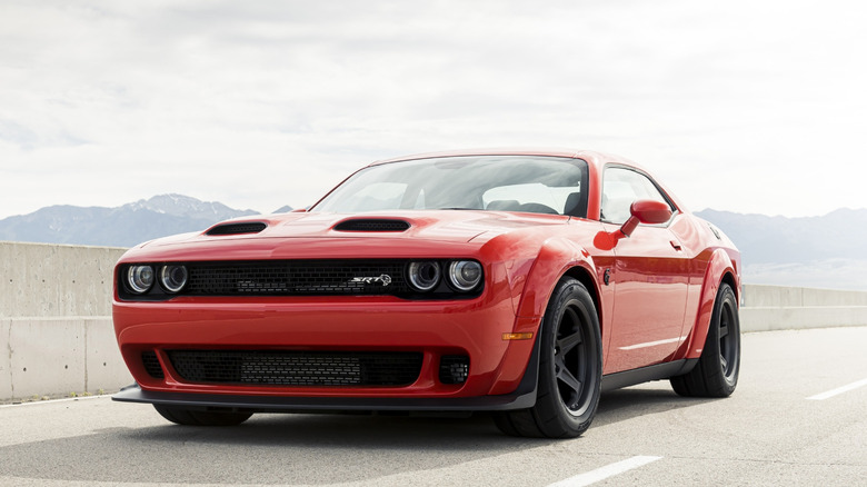 Orange 2020 Dodge Challenger SRT Super Stock drag racer left front three-quarter view by a track wall