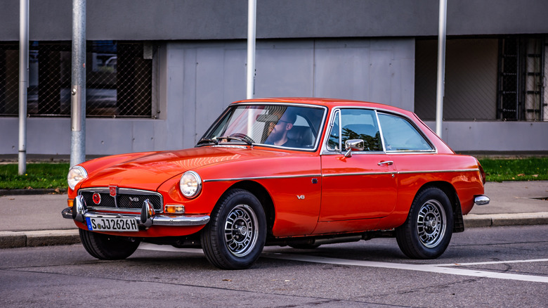 An MGB GT V8 painted in red parked on the roadside.