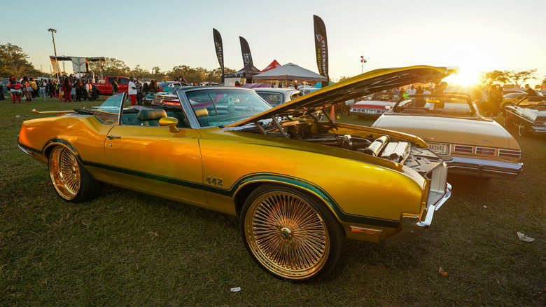 Golden-painted donk showcased at a car show.