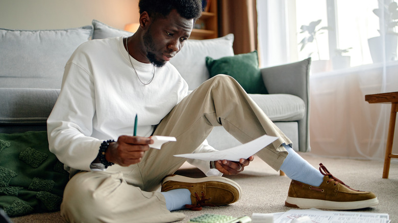 A man reviews paperwork on the floor.