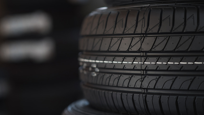 A close-up of a car tire shows tread.