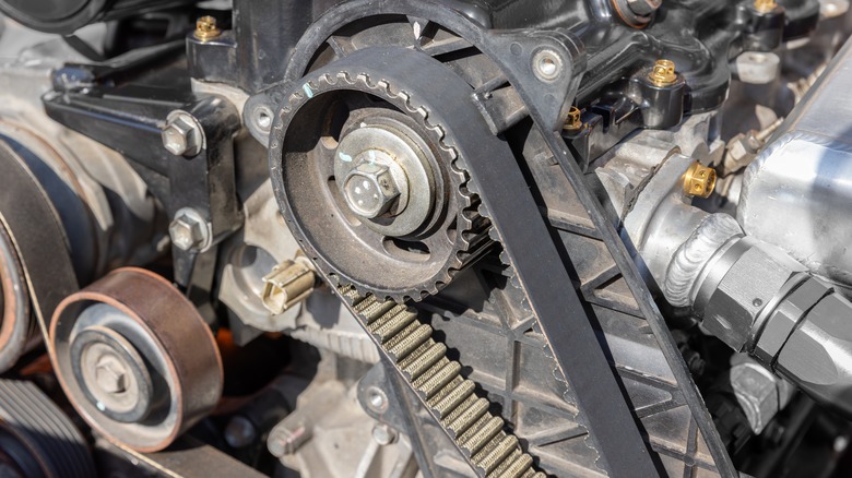 A close-up of an engine shows the crankshaft and timing belt.