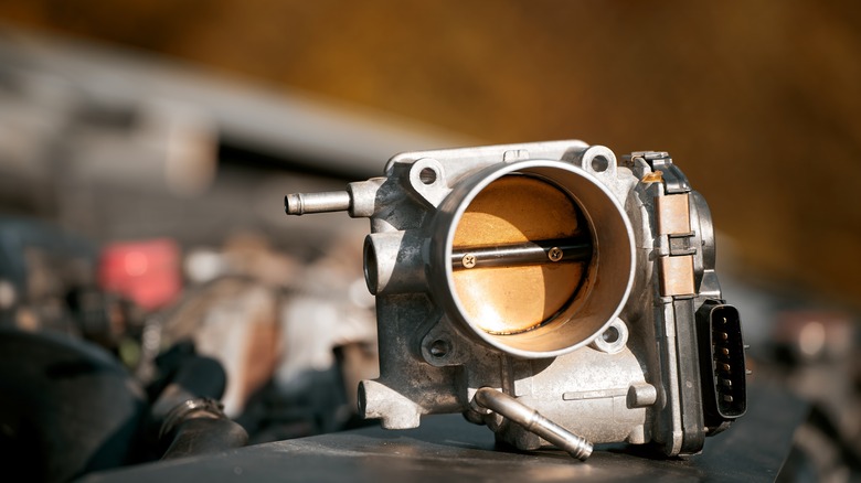 A close-up shows an exposed and disconnected electronic throttle body.