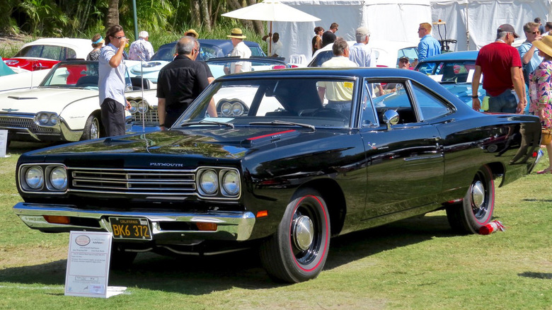 A black 1969 Hemi Road Runner sits on a grass car show lot.