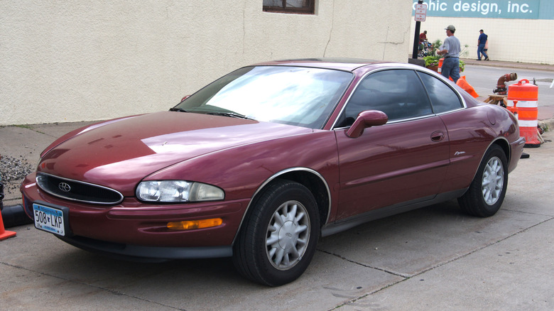 Three-quarter front image of a red 1995 Buick Riviera parked streeside.