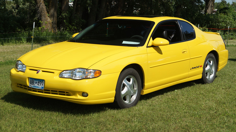 A yellow 2003 Chevrolet Monte Carlo SS parked on grass.
