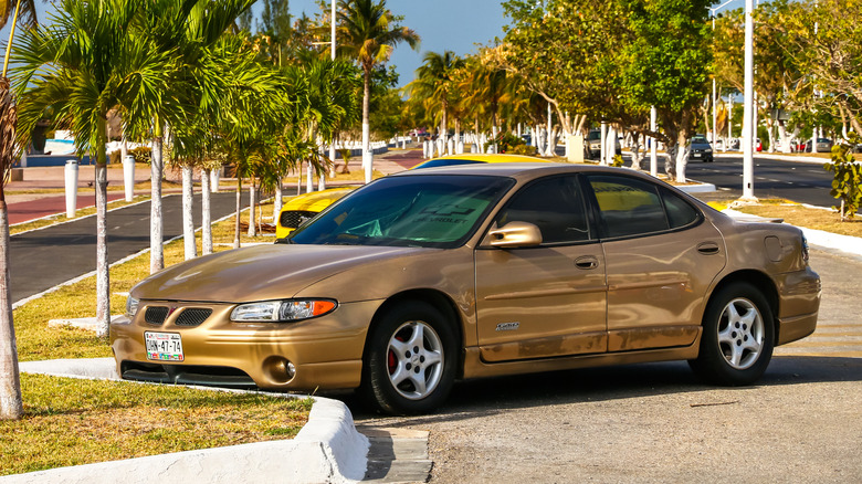 A golden Pontiac Grand Prix GTP pictured in a sunny parking lot.