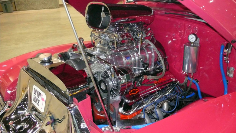 Close-up of a supercharged V8 engine inside a Chevy vehicle, with a sticker that reads, "Do Not Touch" and a decorative flamingo.