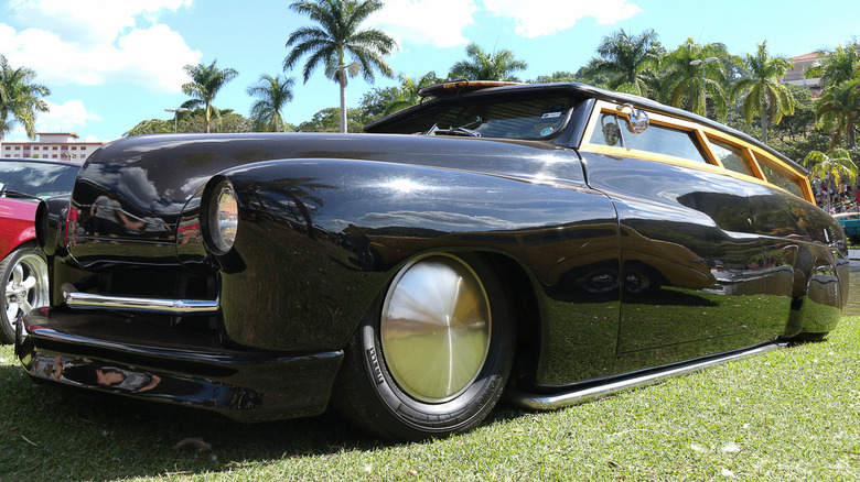 Black lead sled with shaved door handles, nosed hood, and frenched headlights, with palm trees in the background.