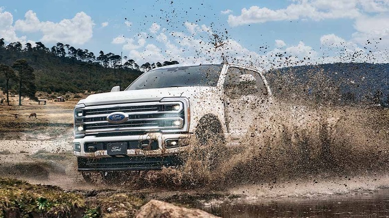 A white Ford F-250 splashes through water.