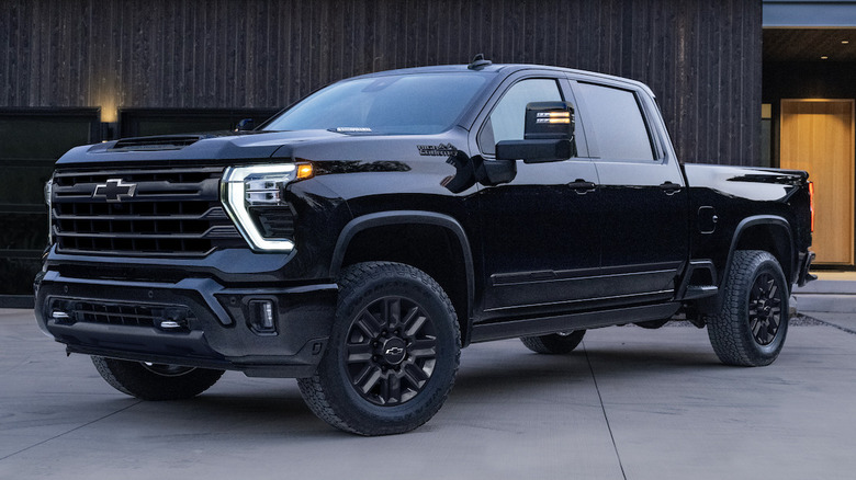 A black Chevy Silverado sits parked in a driveway at dusk.