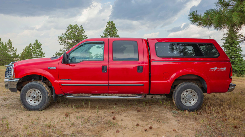 A red Ford F-250 Super Duty sits slightly dirty in a field.