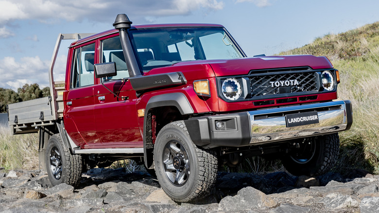 A red Toyota Land Cruiser 70 navigates some rocks.