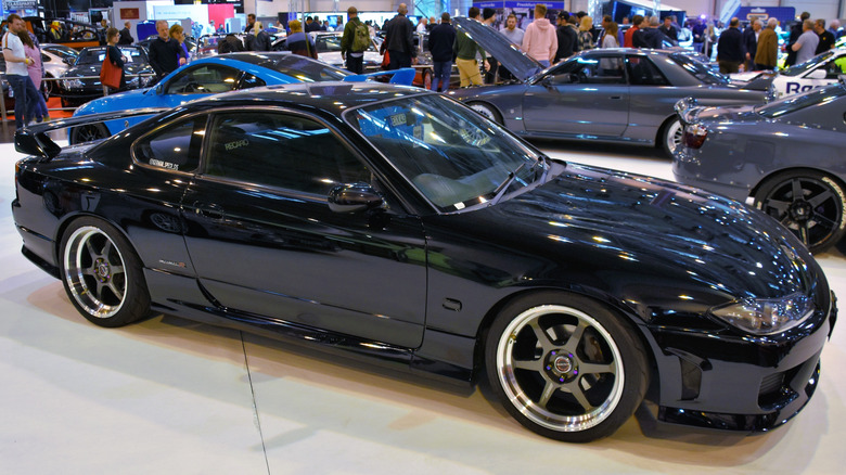 A black Nissan Silvia S15 Spec-R indoors at a car show.