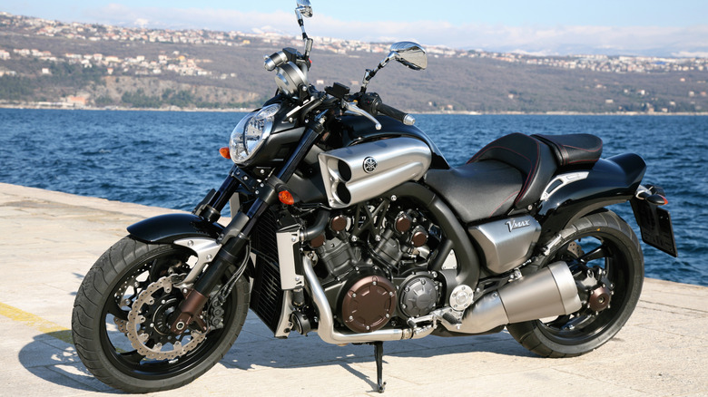 A silver and black Yamaha VMAX parked in front of water
