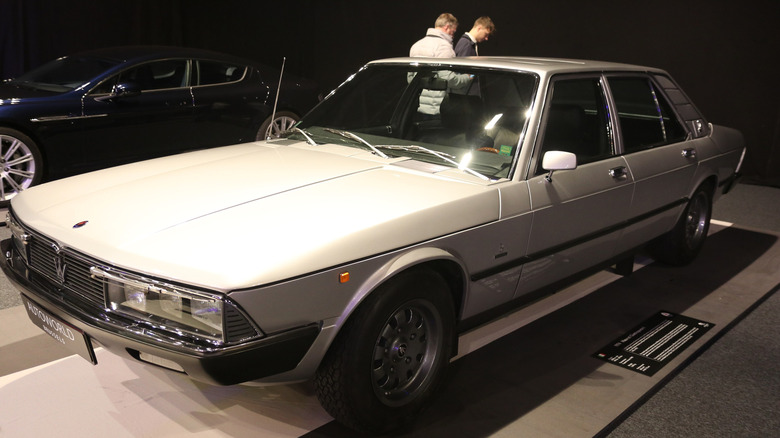 A silver-grey 1974 Maserati Quattroporte II luxury sedan on display at the Autoworld Brussels museum.