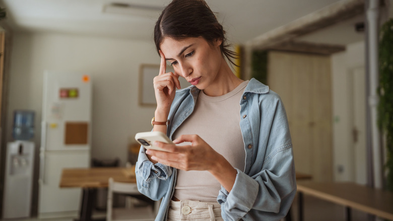 A woman uses her phone thoughtfully.