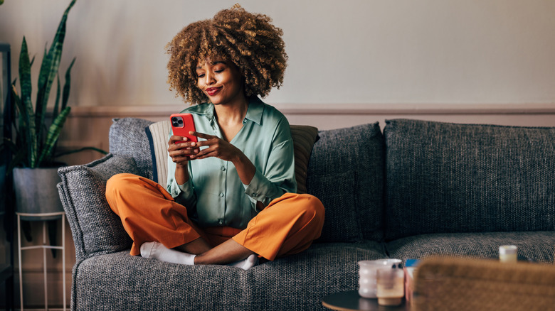 A woman uses her phone on the couch.