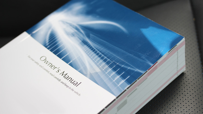 A car's owner's manual sits on an automotive seat.