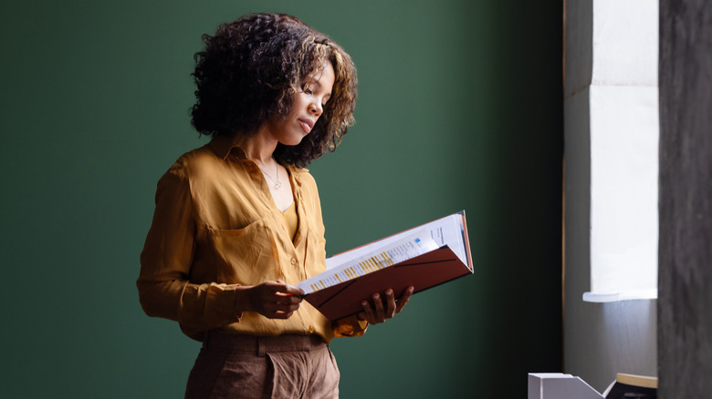 A woman looks at a folder full of papers.