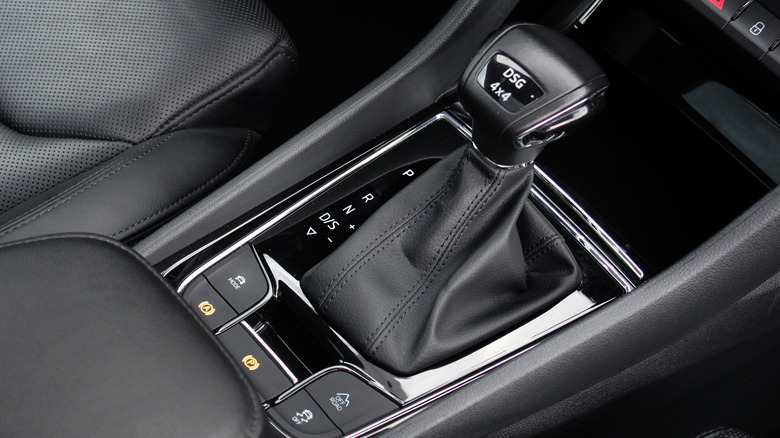 A gear shift lever with a leather boot is shown up close in a center console.