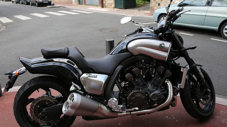 A Yamaha VMAX motorcycle sits near a road in black with brushed chrome accents.