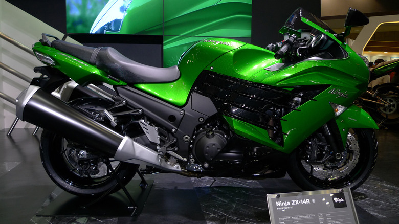 A green Kawasaki Ninja ZX-14R shines under lights on display with a plaque in front.