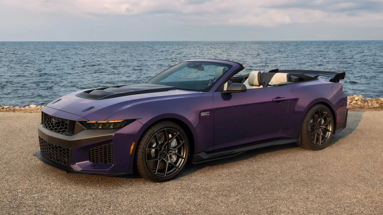 A purple 2027 Ford Mustang Dark Horse SC parked near water under a cloudy sky.